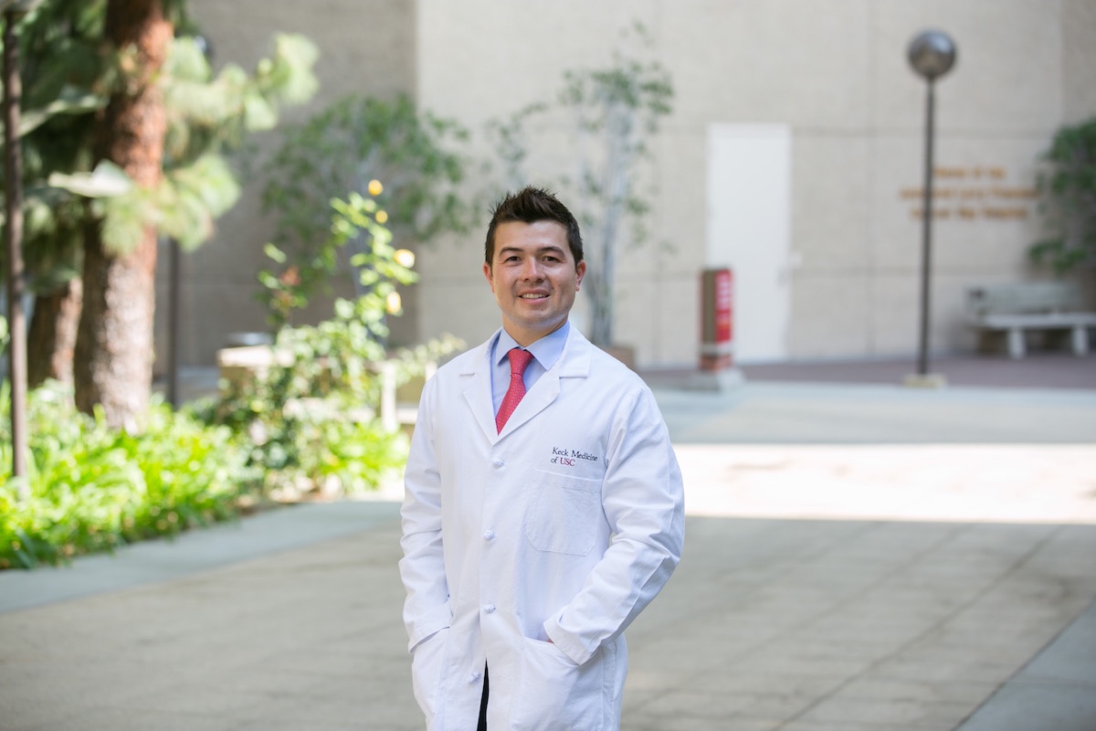 Dr. Jeffrey Loh-Doyle in a white physician coat outdoors